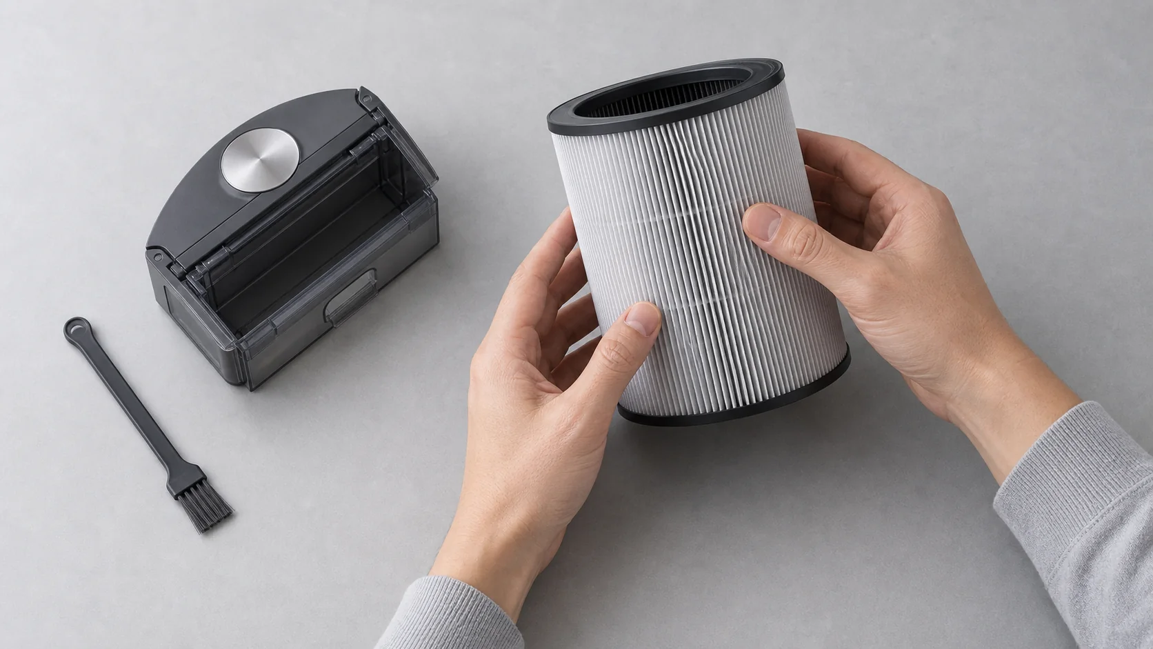 Hands checking a purifier filter beside a robot dust bin and cleaning brush
